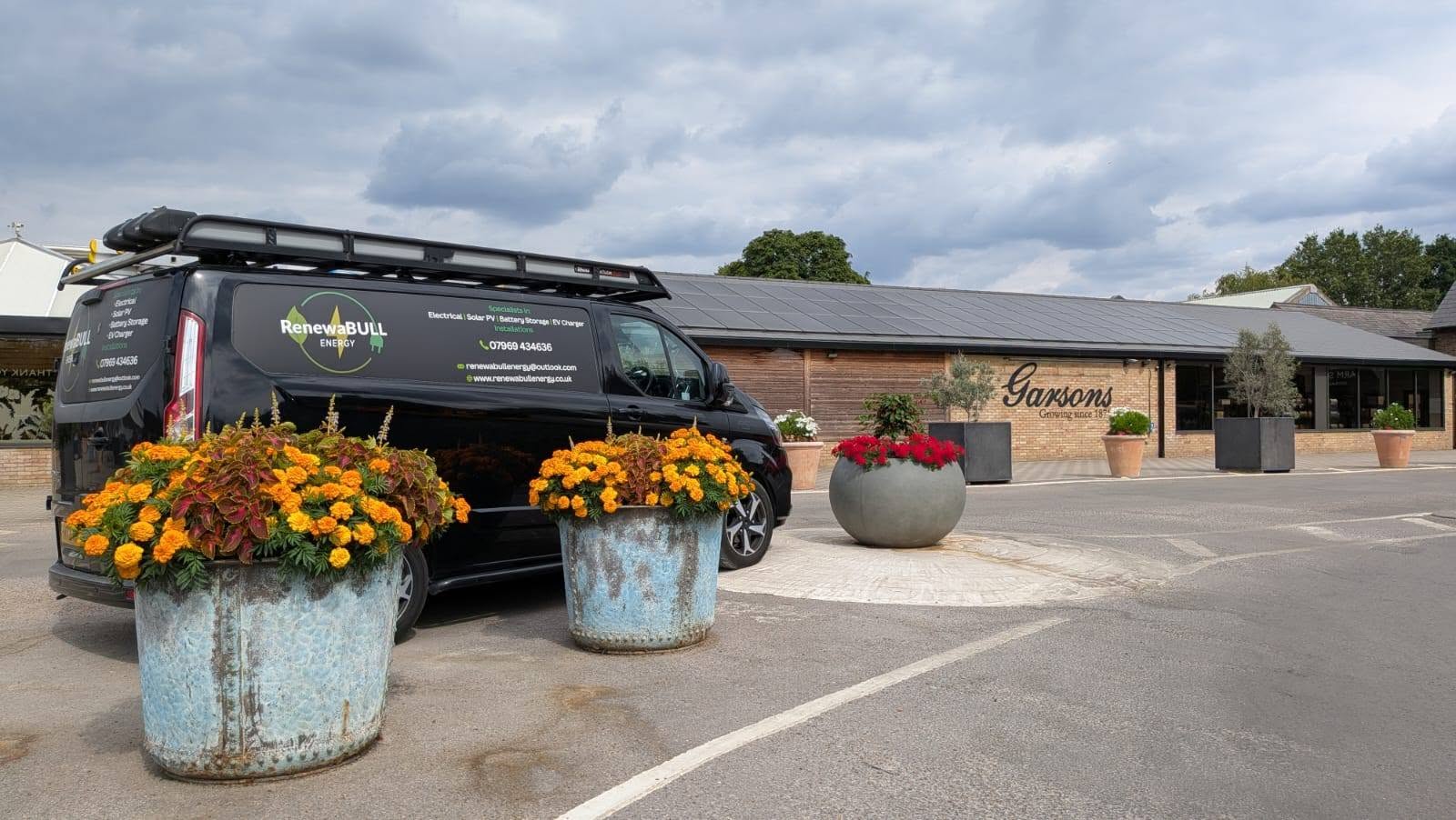 RenewaBULL installation van outside Garsons in Esher, beneath its rooftop solar panels.