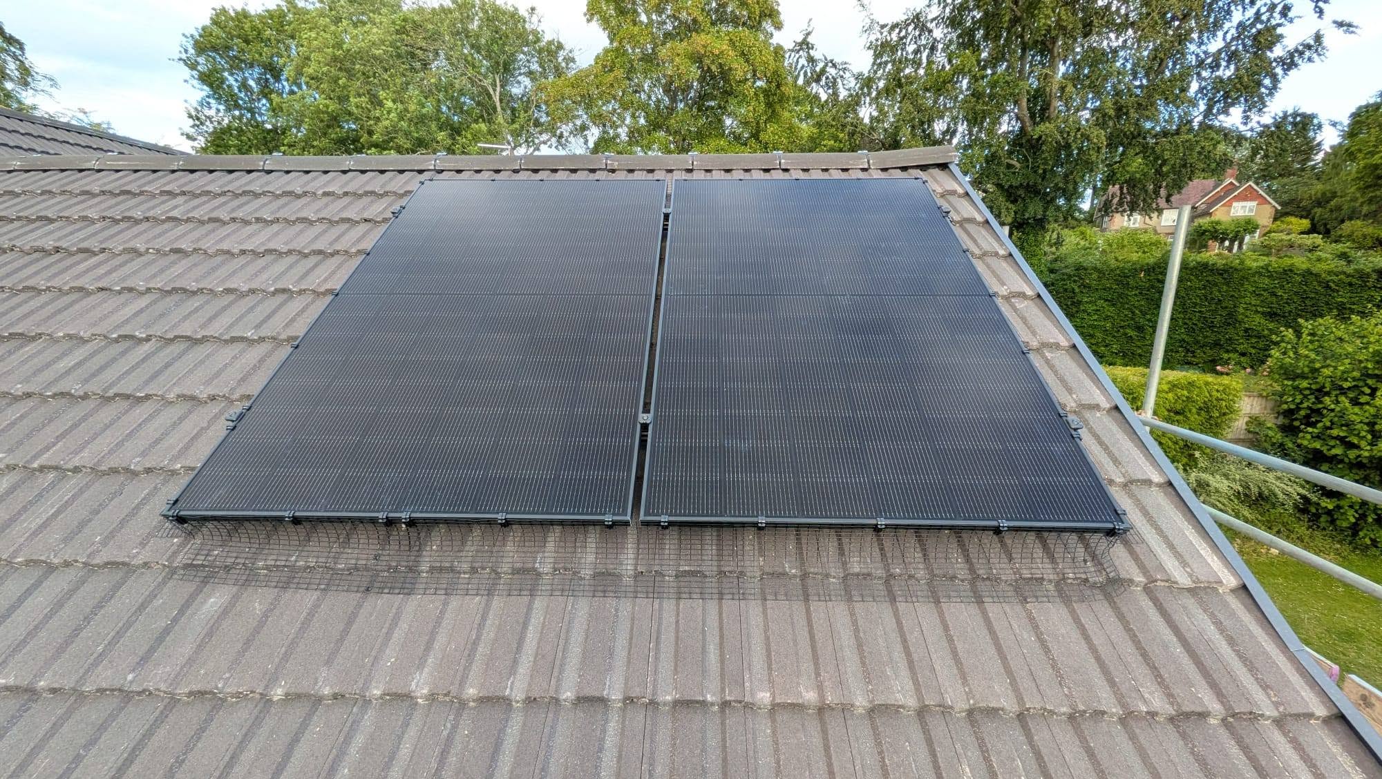 Two dark solar panels mounted on a grey tiled residential roof.